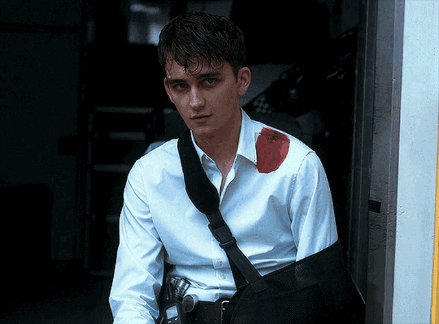 a man wearing a white shirt with a black strap around his shoulder