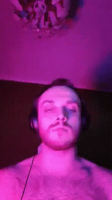 a man wearing headphones is standing in front of a purple background