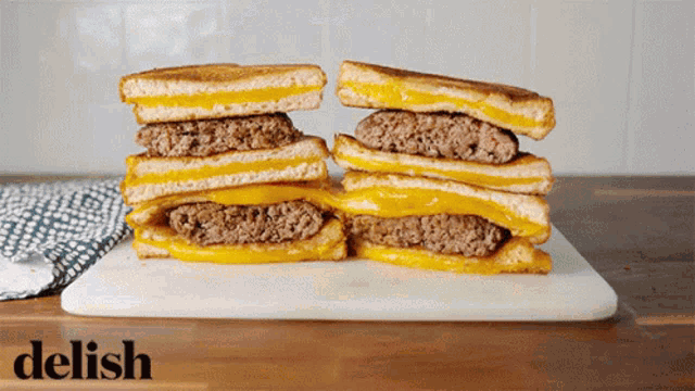 two grilled cheese sandwiches stacked on top of each other on a cutting board