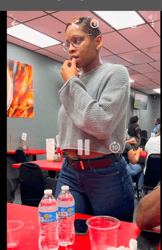 a woman sits at a table with two bottles of aquafina water on it