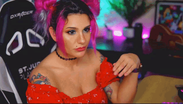 a woman with pink hair is sitting in a chair that says dxracer