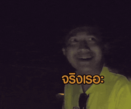 a man in a yellow shirt is making a funny face in a dark room with a foreign language caption