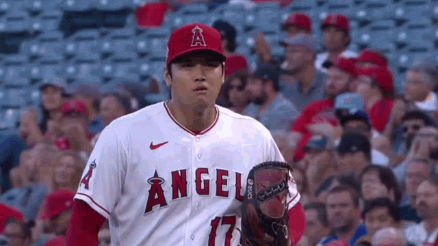 a baseball player is standing in front of a crowd holding a glove .