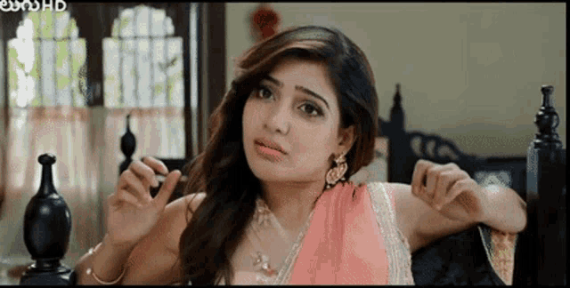 a woman in a pink saree is sitting on a bed with her arms outstretched