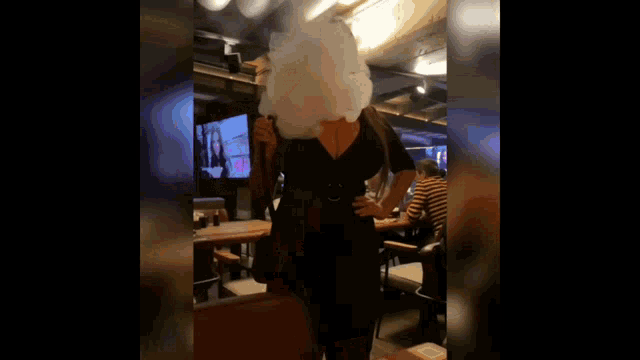 a woman is smoking a hookah in a restaurant while wearing a black dress .