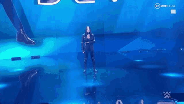 a woman is standing on a stage in front of a large screen while a man is standing behind her .