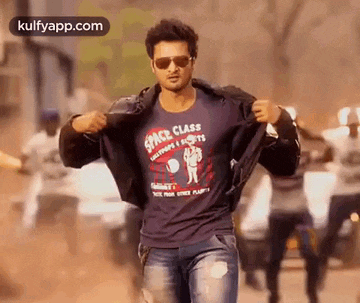a man wearing sunglasses and a t-shirt with the word space class on it is walking down a street .