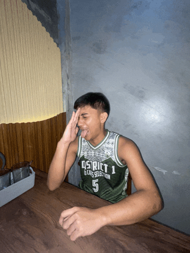 a young man wearing a district 1 jersey sitting at a table