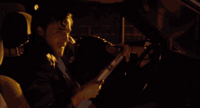 a man is smoking a cigarette while sitting in the driver 's seat of a car