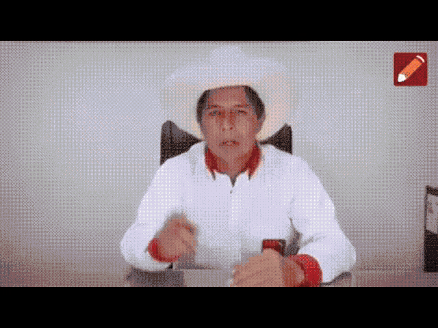 a man wearing a white hat and a white shirt is sitting at a desk giving a speech .