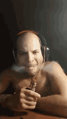 a shirtless man wearing headphones is smoking a cigarette