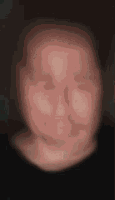 a blurry picture of a person 's face with a black shirt on