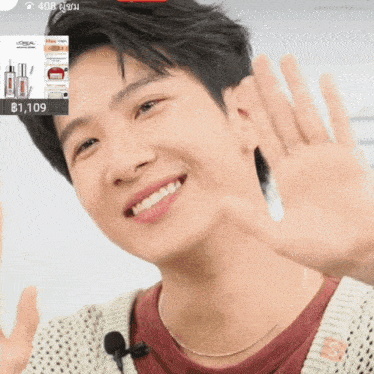 a man is smiling and waving his hand in front of a loreal advertisement