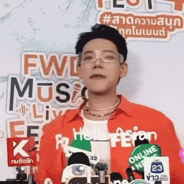 a man wearing glasses is standing in front of a microphone at a press conference .