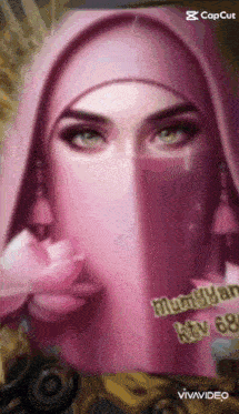 a woman wearing a pink hijab is holding a flower in her hand