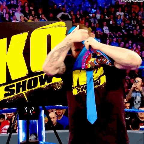 a man is wearing a blue tie in front of a sign that says ko show .