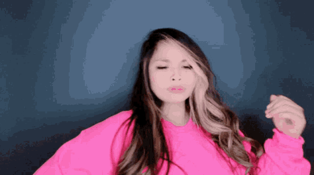 a woman in a pink sweater is making a face