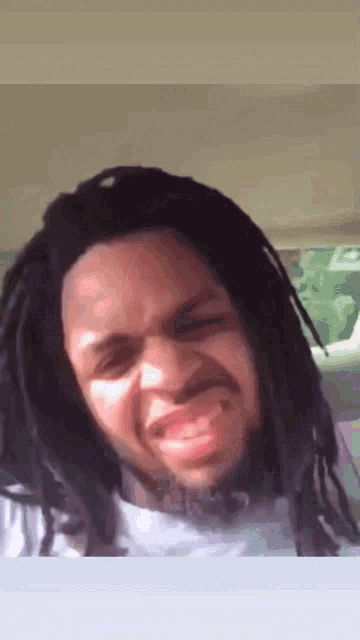 a man with dreadlocks is making a funny face in a car
