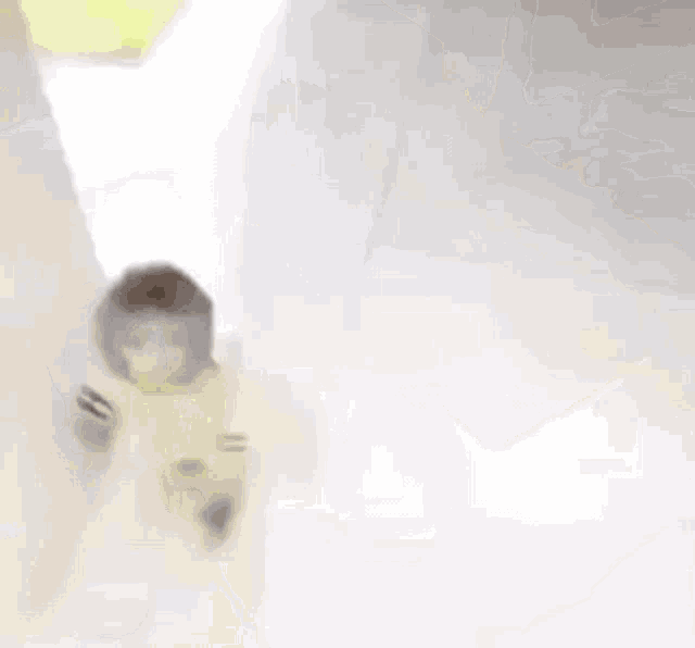 a monkey in a yellow outfit is walking on a white surface .