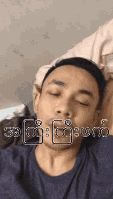 a man laying on a bed with his eyes closed and a foreign language written on his face .