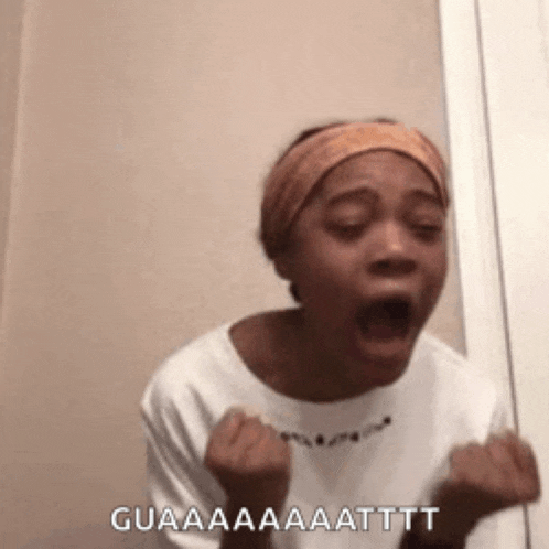 a woman wearing a headband is screaming with her mouth open and her hands in the air .