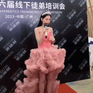 a woman in a pink dress holds a microphone in front of a wall that says sanman