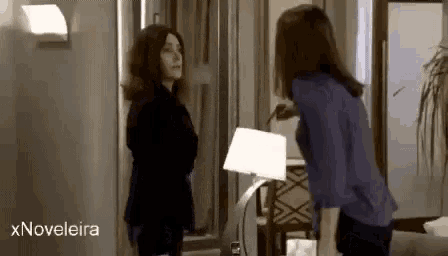 two women are standing next to each other in a living room with the words xnovelaira in the corner