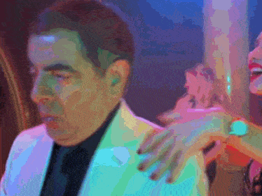 a man in a white suit has a woman 's arm around his shoulder