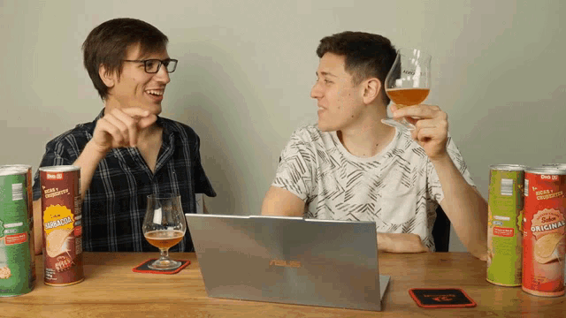two men are sitting at a table with chips and a laptop that says asus on it