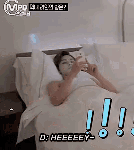 a woman is laying in bed looking at her phone and says " d : heeeey "