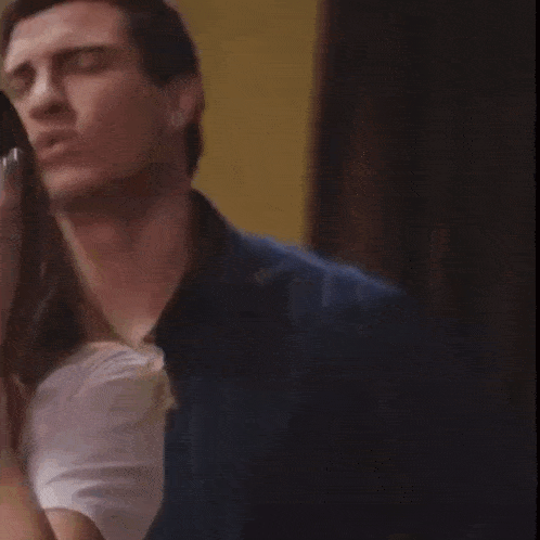 a man in a blue shirt is standing next to a woman in a white shirt and making a funny face .