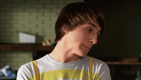 a young man wearing a grey and yellow striped shirt looks down