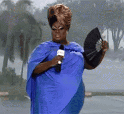 a woman in a blue dress holding a microphone and a fan