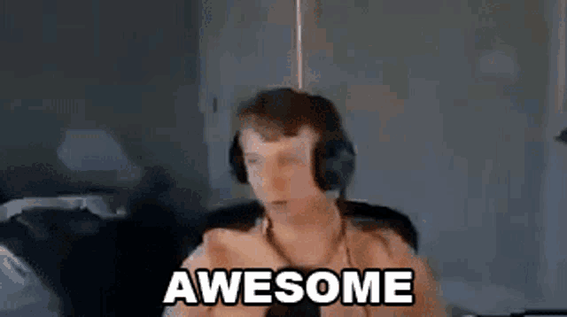 a man wearing headphones is giving a thumbs up and the words awesome are visible behind him .