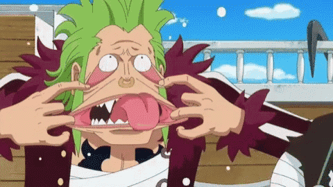 a man with green hair is sticking his tongue out .