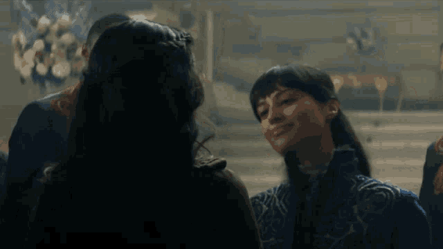 a woman in a blue jacket is smiling at another woman