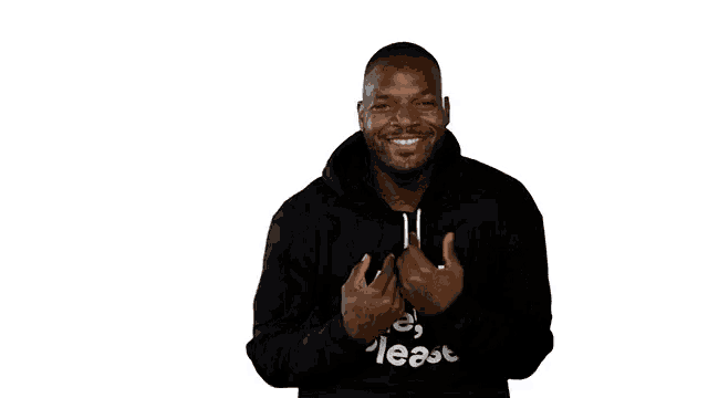 a man wearing a black hoodie that says `` in me please '' is smiling and giving a thumbs up .