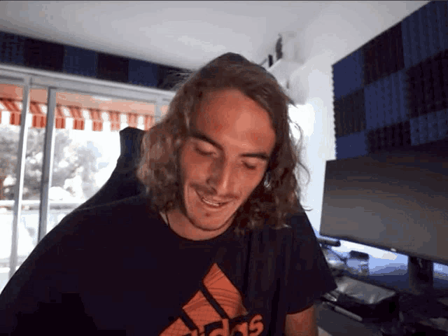 a man with long hair wearing a black adidas shirt