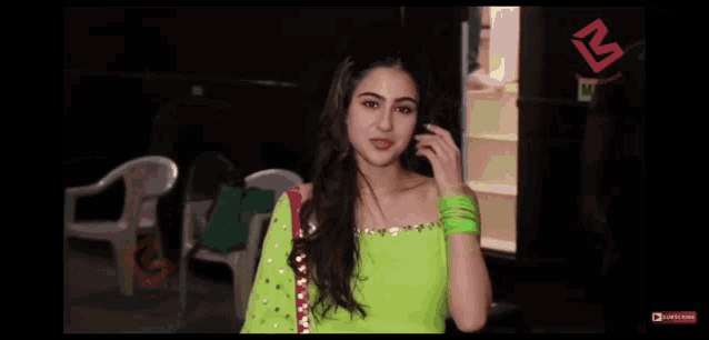 a woman in a neon green dress is making a call sign with her hand