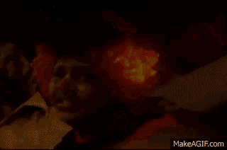 a clown in a red wig is smiling in front of a man with a beard