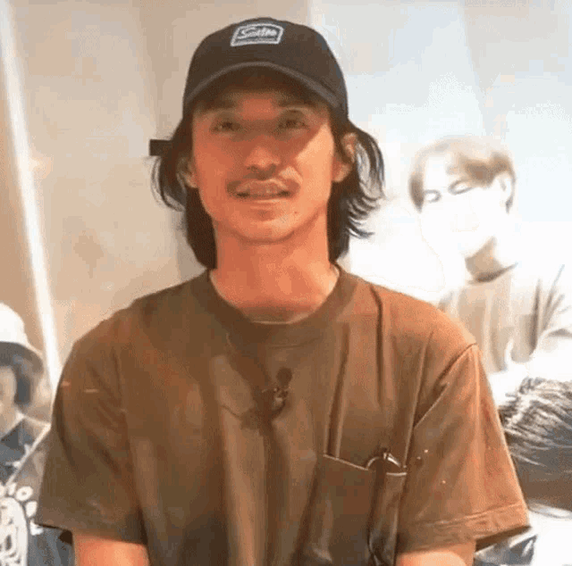 a man wearing a black hat and a brown t-shirt