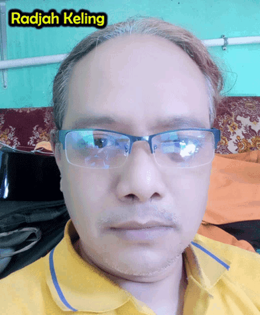 a man wearing glasses and a yellow shirt has radjah keling written above his head