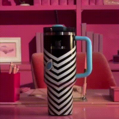 a black and white striped mug with a blue handle sits on a desk