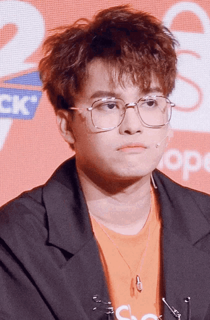 a young man wearing glasses and an orange shirt with the word supreme on the front