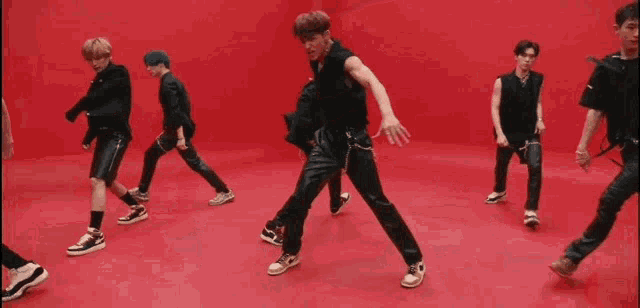 a group of men are dancing together in a red room .