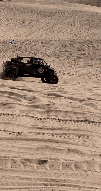 a jeep is driving through a sandy desert with a flag that says red bull