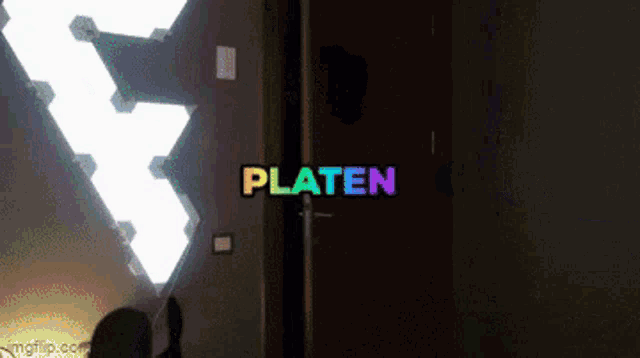 a rainbow colored sign that says platen in a dark room