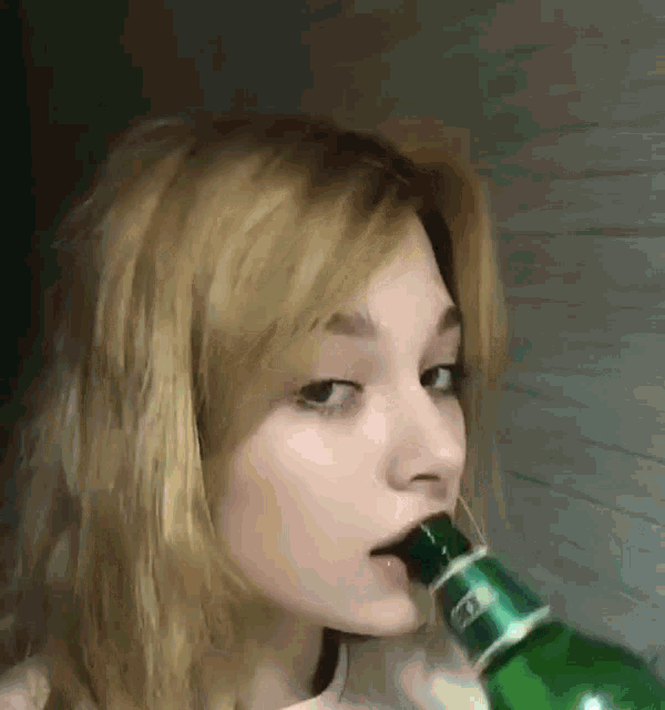 a woman is drinking from a green bottle with a green cap .