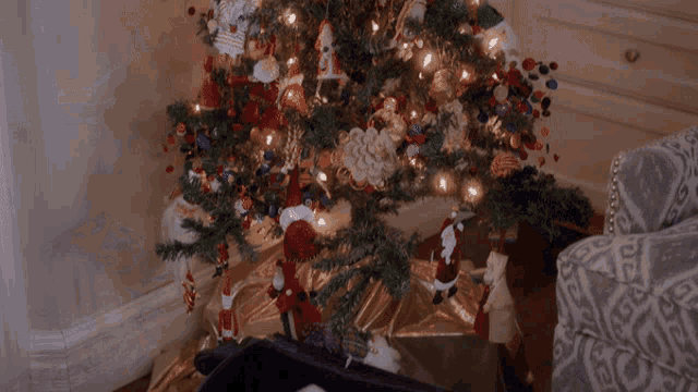a small dog is laying under a christmas tree in a suitcase