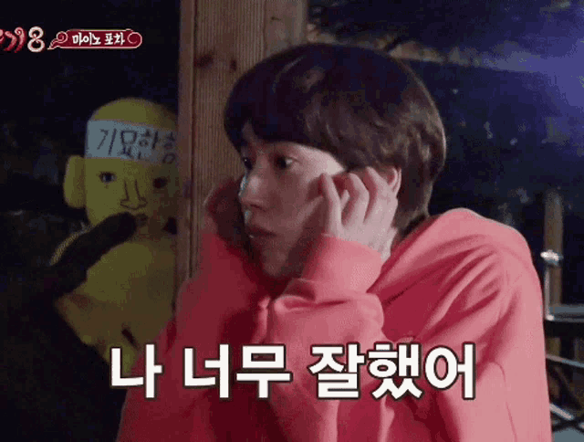 a man wearing a red sweatshirt is talking on a cell phone in korean